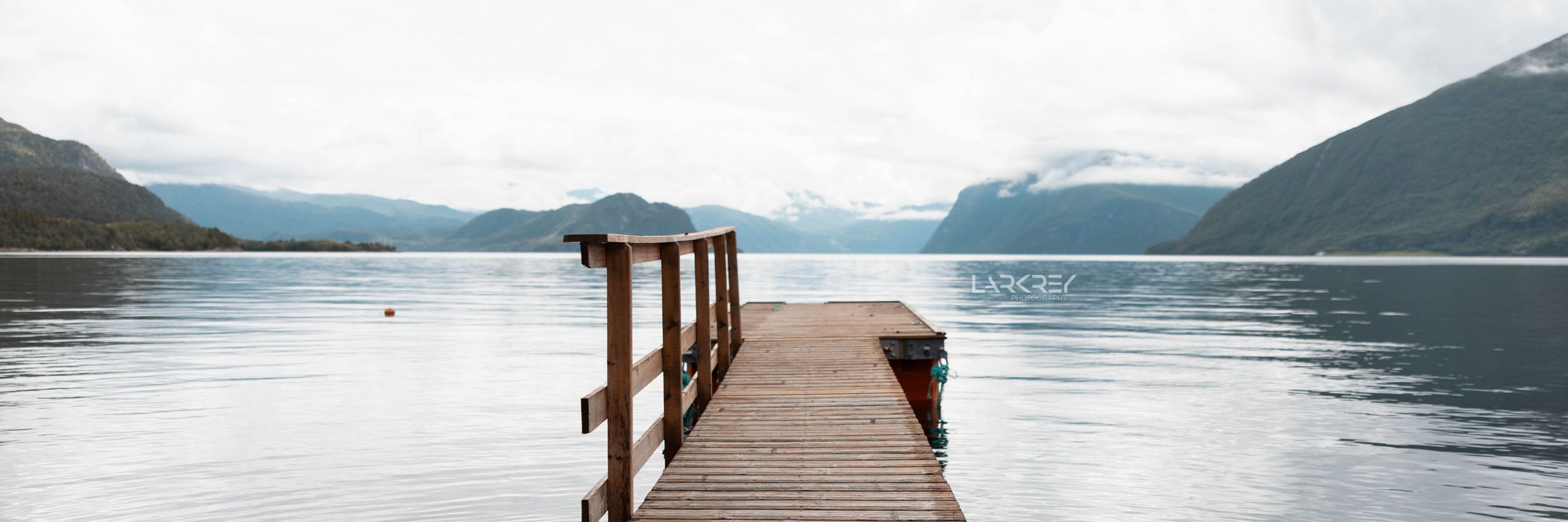 Steg im Fjord mit schneebedeckten Bergen im Hintergrund